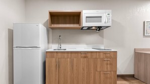 Una cocina compacta con un refrigerador blanco, un microondas y armarios de madera.