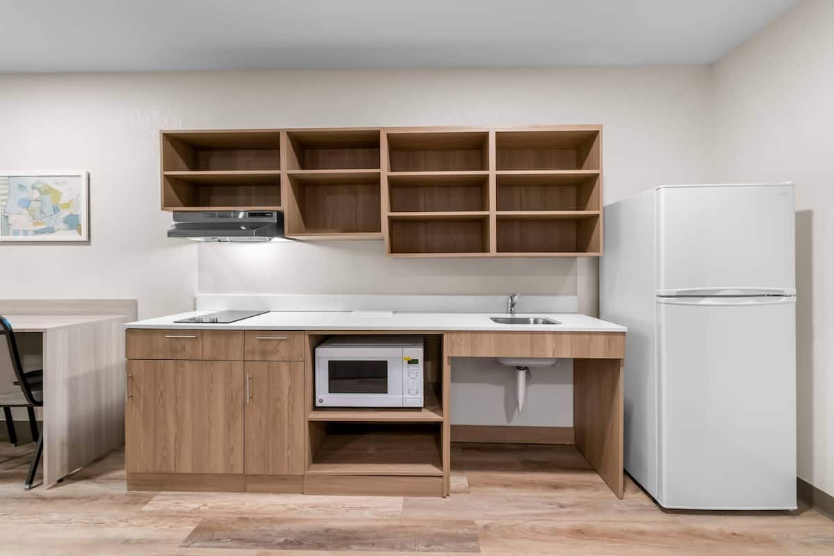 Una cocina compacta con armarios de madera, un microondas, un lavabo y un refrigerador blanco.