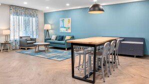 Una sala de estar moderna con una pared azul de acento, una mesa de comedor de madera y un sofá gris.