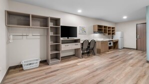 Una cocina moderna con electrodomésticos integrados, una zona de comedor y estanterías abiertas.