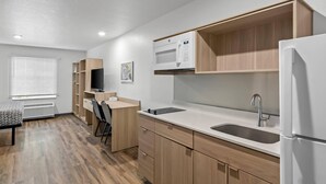 Una cocina moderna con armarios de madera, un microondas, un lavabo y un refrigerador.