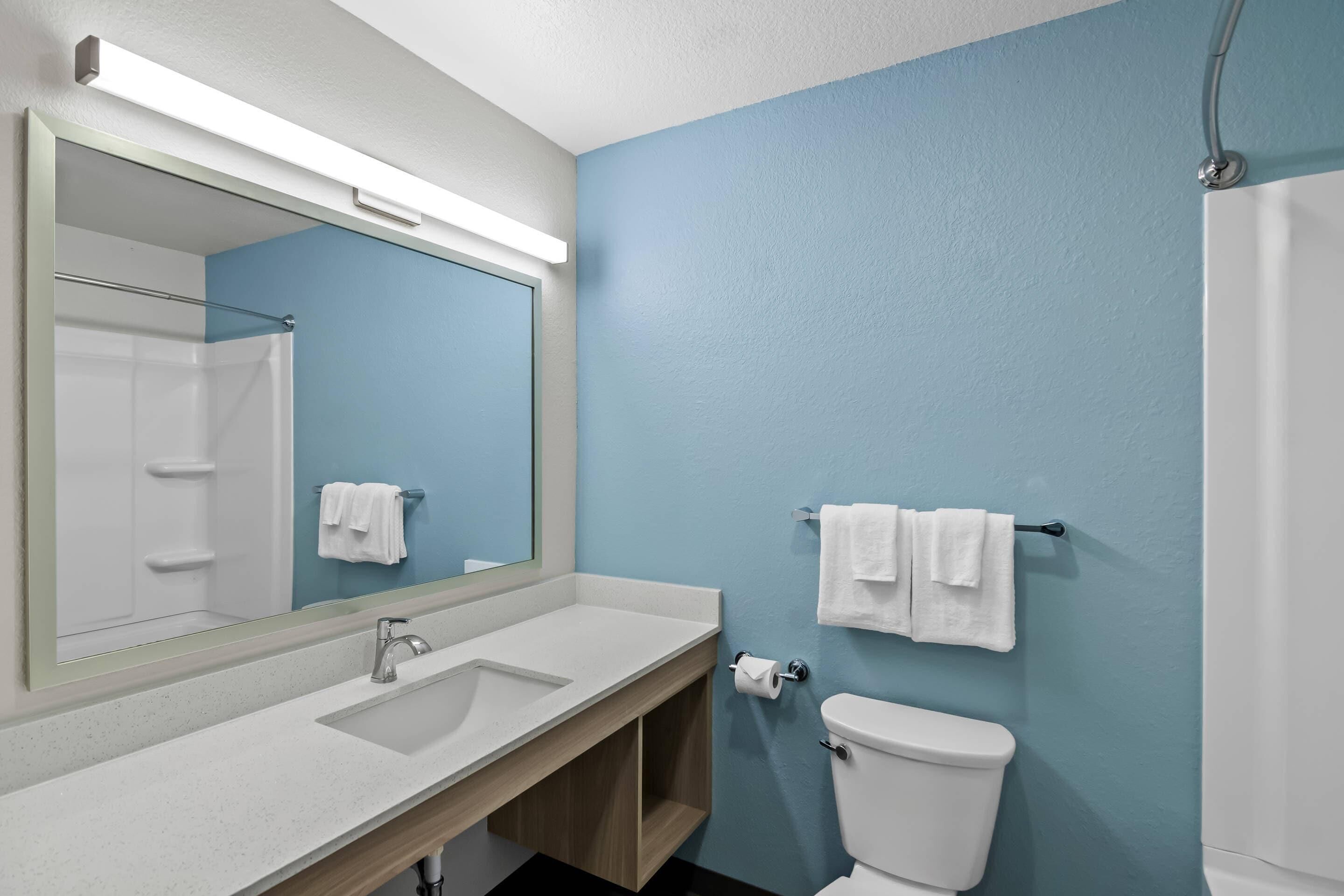 Ein Badezimmer mit Waschbecken, Spiegel, Toilette und Dusche.