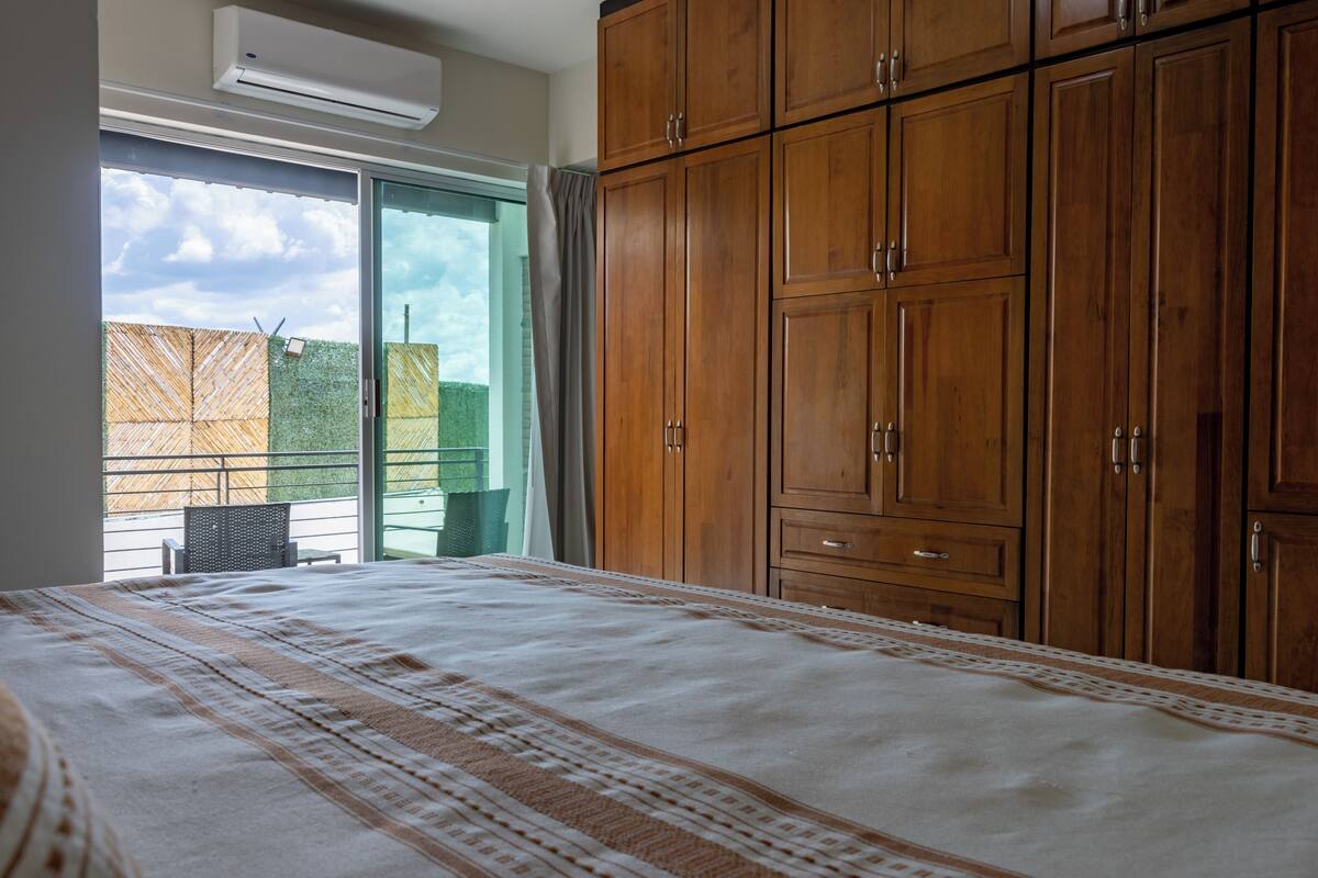 Ein Schlafzimmer mit einem großen Bett, einem Holzschrank und einer Glastür, die auf einen Balkon führt.