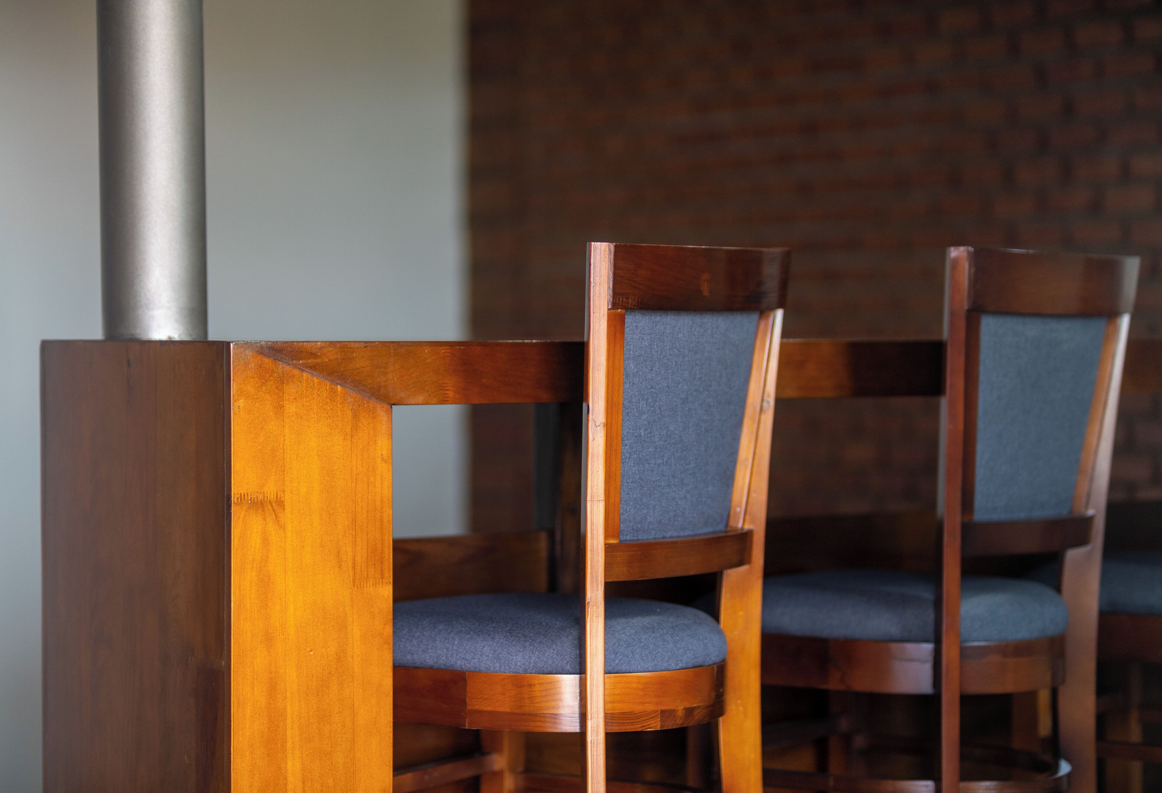 A set of wooden chairs with blue cushions and a metal column.