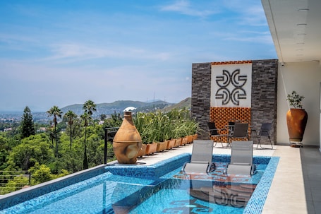 Una piscina al aire libre, sombrillas, sillones reclinables de piscina