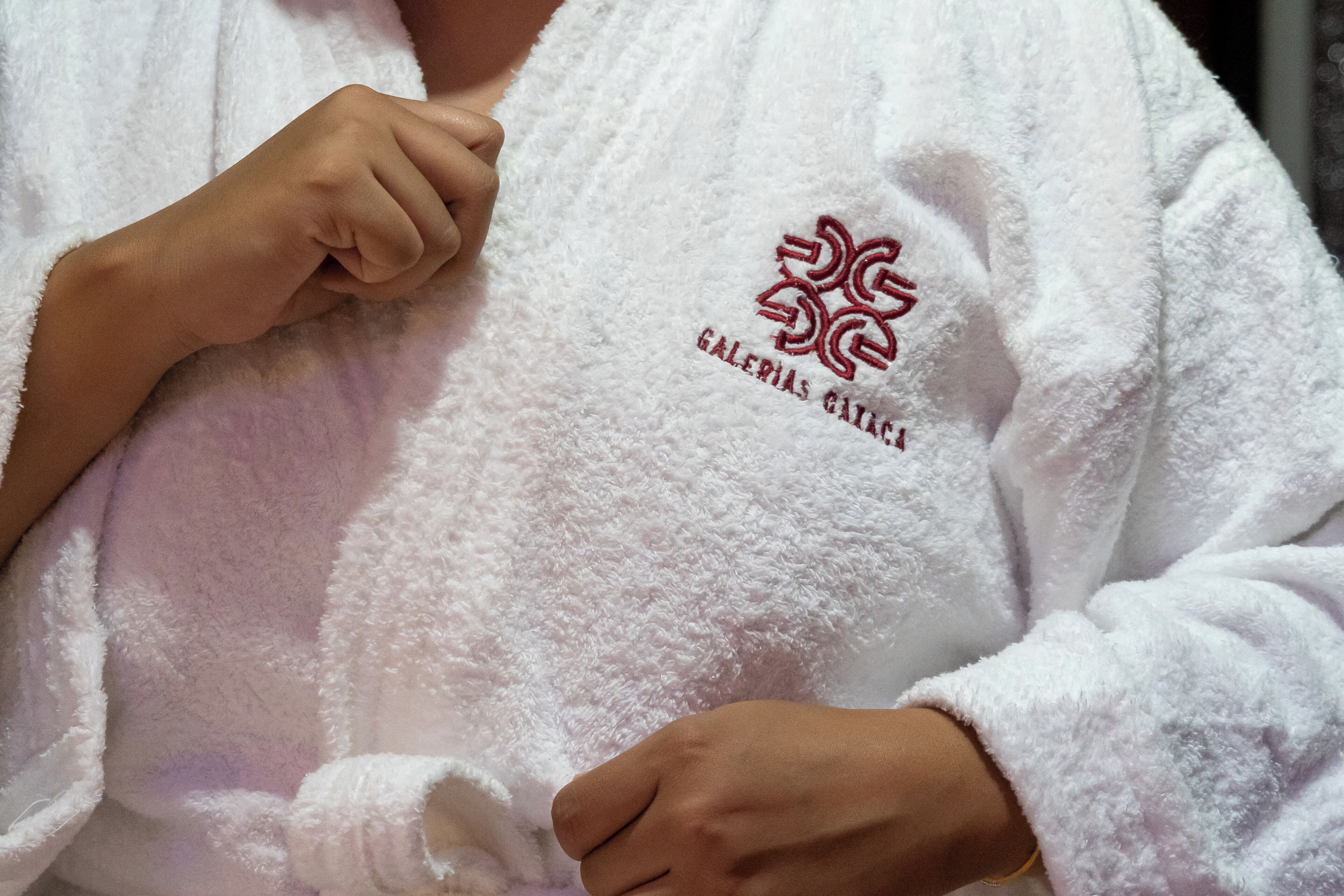 A person wearing a white robe with a logo and text on it.