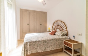 A bedroom with a bed, a nightstand, a wardrobe, and a lamp.