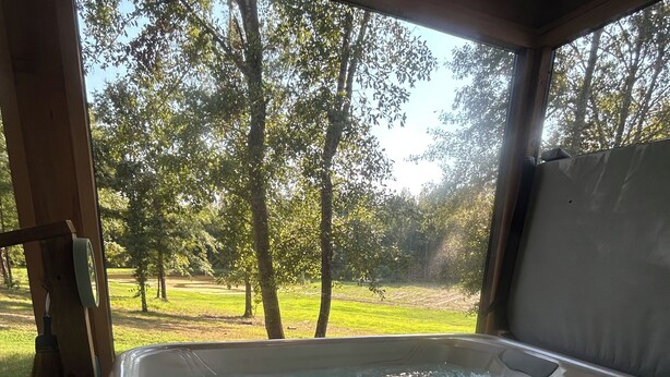 A hot tub with a view of a grassy area and trees.