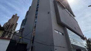 A tall, modern building with a prominent vertical design and a large glass facade.