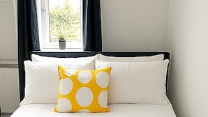 A neatly made bed with white bedding and a yellow towel.