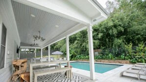Uma área externa coberta com piscina, assentos e piso estampado.