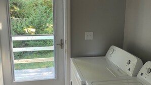 A laundry room with a door leading to a deck, a washing machine, and a dryer.