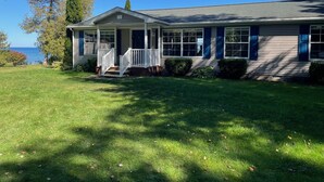 A house with a porch, a view of the sea, and a well-maintained lawn.
