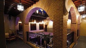 A corridor with high brick arches, a patterned floor, and a balcony with a railing. - Deluxe Double Room (Marrakech)
