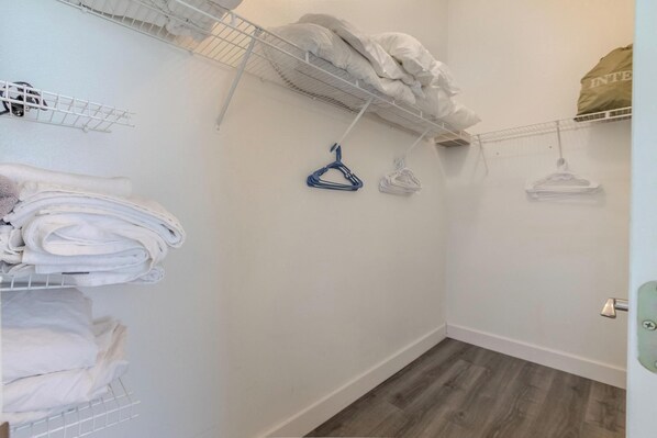 A laundry room with metal shelves, a white wall, and a wooden floor.