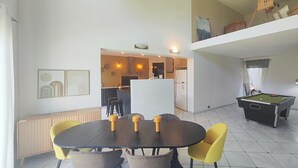 A dining area with a black table and yellow chairs, a kitchen in the background, and a pool table to the right. - Nice home in Usclas-d'Hérault (Usclas-d'Hérault)