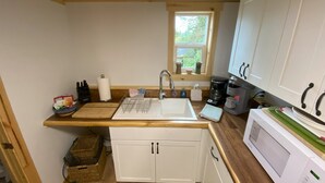 A compact kitchen with a sink, a microwave, and wooden cabinets. - Rustic Homer Cabin w/ Moose Views & Quiet Porch (Homer)