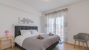 Une chambre à coucher avec un lit, une table de chevet, une chaise et une fenêtre avec des rideaux.