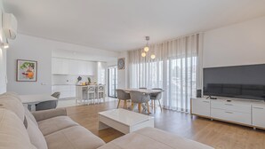 Un salon moderne comprenant un canapé, une table basse, un téléviseur et un coin repas avec des chaises et une table.