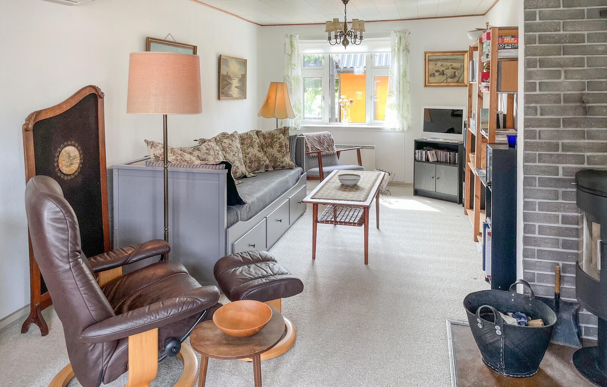 Un salon comprenant un canapé, deux fauteuils en cuir, une table basse, une cheminée, une bibliothèque et un téléviseur.