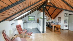 A spacious loft with a high ceiling, a kitchen with white cabinets, a dining area with a wooden table, and a seating area with leather chairs. - Awesome home in Tranekær with WiFi (Tranekær)