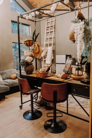 Un salon chaleureux avec un coin repas, doté d’un plafond en bois, d’une échelle et d’un décor de style rustique.