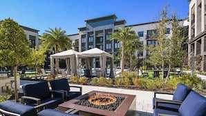 Un patio en la azotea con mobiliario exterior, una chimenea y vistas a edificios modernos.
