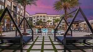 Un patio de hotel con piscina, sillas de descanso y palmeras.