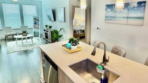 Una cocina moderna con una isla central, un lavaplatos integrado y un comedor con sillas.