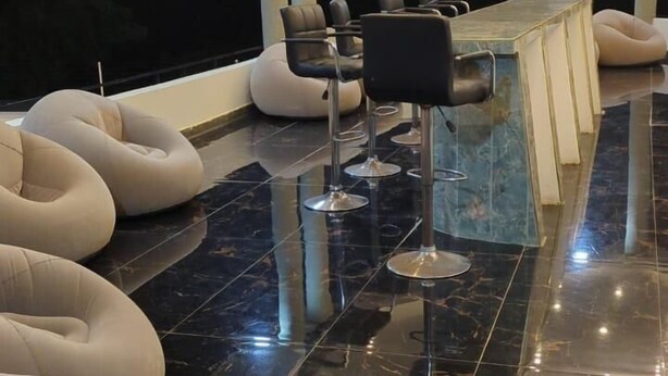 Ein moderner Lounge-Bereich mit schwarzem Marmorboden, weißen Sitzsäcken und einem langen Tisch.
