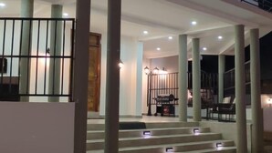 Ein modernes Gebäude mit überdachtem Außenbereich, Stufen zu einem Balkon und mehreren Säulen.