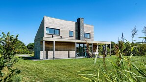 A modern house with a sloped roof, large windows, and a covered patio area. - 3 bedroom amazing home in Kamperland (Kamperland)