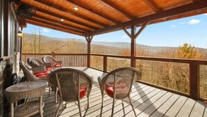 A covered deck with wicker chairs and a view of the surrounding landscape. - Cabin with Long Range Views, Hot Tub, Game Room (Beech Mountain)
