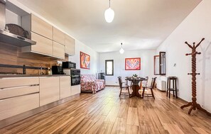 Una cocina moderna con armarios de madera, un comedor con mesa y sillas, y un perchero.