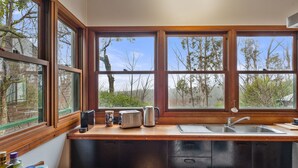 A kitchen with wooden countertops, a sink, and a window overlooking a forested area. - Blackheath Breeze Cottage - Nature Escape (Blackheath)