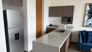 Een moderne keuken met een roestvrijstalen koelkast, een magnetron, een spoelbak en een aanrecht.