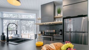 A modern kitchen with a large island, stainless steel appliances, and a view of a snowy landscape.