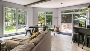 A spacious living area with a large sofa, a dining table, and a kitchen area with a bar.
