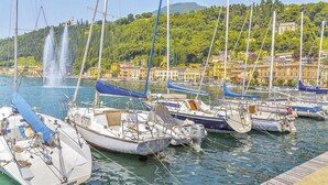 Un port de plaisance avec des bateaux amarrés, une fontaine en arrière-plan et des bâtiments dotés de balcons donnant sur l’eau.