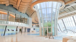 Un vaste atrium doté d’un haut plafond, de grandes fenêtres et d’un élément décoratif central composé d’eau.