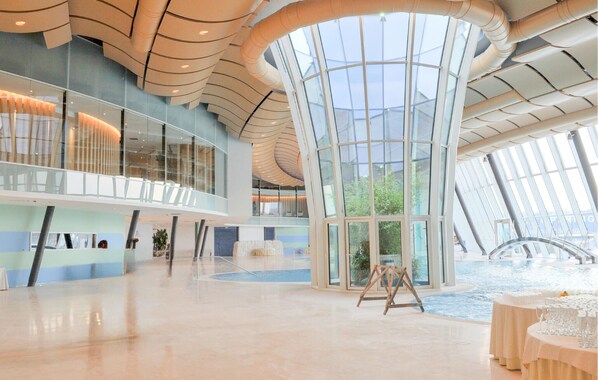 Un vaste atrium doté d’un haut plafond, de grandes fenêtres et d’un élément décoratif central composé d’eau.