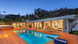 A modern house with a swimming pool, large glass windows, and a wooden deck. - Luxe Hollywood Hills Modern, City Views, 84°F Pool (Los Angeles)