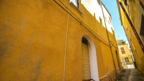 A narrow alleyway with yellow buildings, a stone wall, and a small door. - Awesome home in Venafro with WiFi (Venafro)