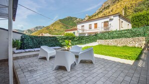 An outdoor patio with two white plastic chairs and a small table, surrounded by a stone wall and a green hedge. - Awesome home in Venafro with WiFi (Venafro)