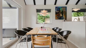 A dining area with a wooden table, black chairs, pendant lights, and a painting on the wall. - 3 bedroom amazing home in Lundby (Lundby)