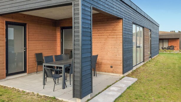 Une maison moderne dotée d’un patio couvert, d’un coin repas avec une table et des chaises, et d’une grande fenêtre.