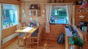 A wooden cabin interior with a dining table, chairs, a kitchen area, and a window with a view of the outside. - Stunning home in Korssund with WiFi (Korssund)