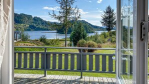 A wooden deck with a railing overlooking a lake and forested hills. - Stunning home in Korssund with WiFi (Korssund)