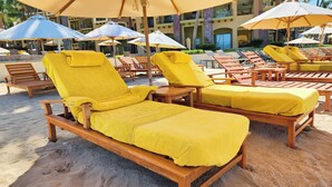 A beachside lounge area with wooden lounge chairs and yellow towels, surrounded by umbrellas. -  2 Bedroom condo in Villa la Estancia in Nuevo Nayarit (Nuevo Nayarit)