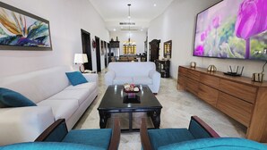A modern living room with a white sofa, a coffee table, and a TV on the wall. -  2 Bedroom condo in Villa la Estancia in Nuevo Nayarit (Nuevo Nayarit)